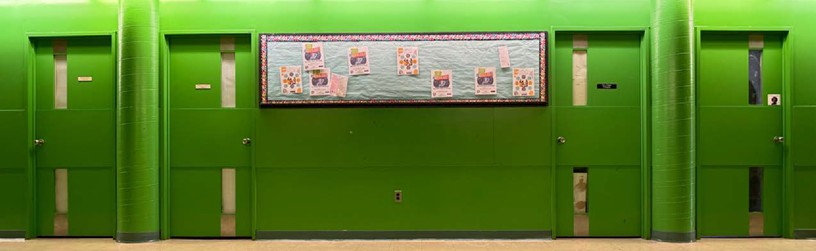 Photo of the green cluster hallway with four doors and a bulleting board on the wall.