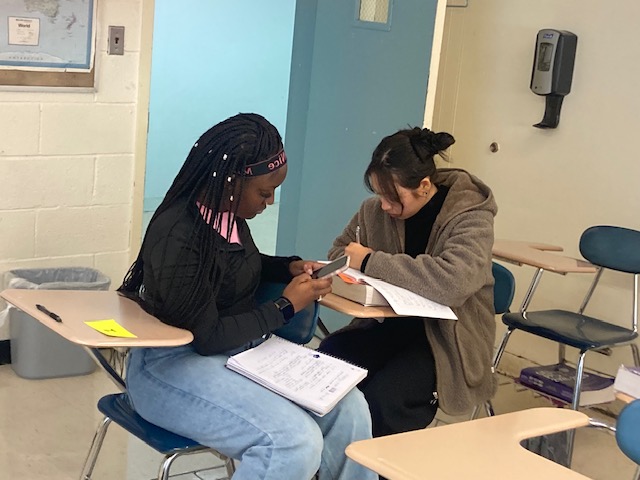 Two students in a classroom working at their desks