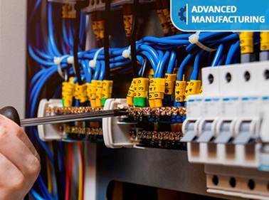 A bunch of colorful cables and a hand holding a screwdriver.
