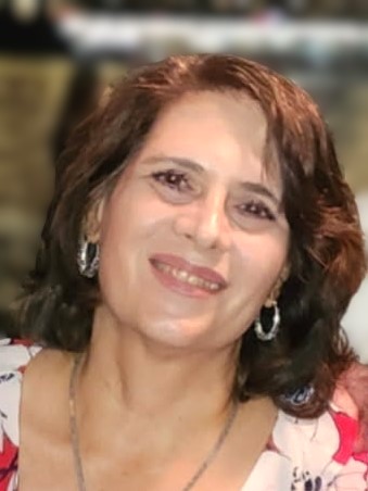 Photo of a woman with dark, shoulder-length hair and hoop earrings, wearing a floral top, and smiling.